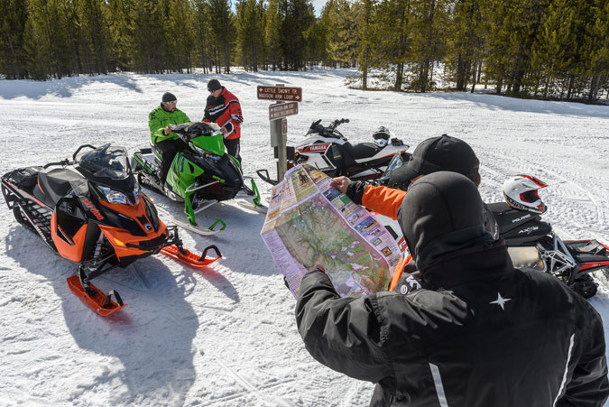 Snowmobilers looking at a map